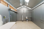 Changing Places interior showing hoist with room coverage, toilet pan and cistern with back rest and grab rails, adult change table and shower with bench